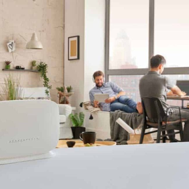 Router interior room on the table and two man is accessing WiFi.